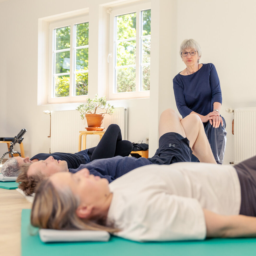 Die Teilnehmer der Feldenkrais Kurse liegen auf dem Boden und machen eine Übung | Physiotherapie Schmeddes