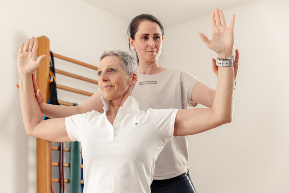 Physiotherapie Hausbesuche | eine Patientin bekommt von einer Physiotherapeutin eine Übung gezeigt
