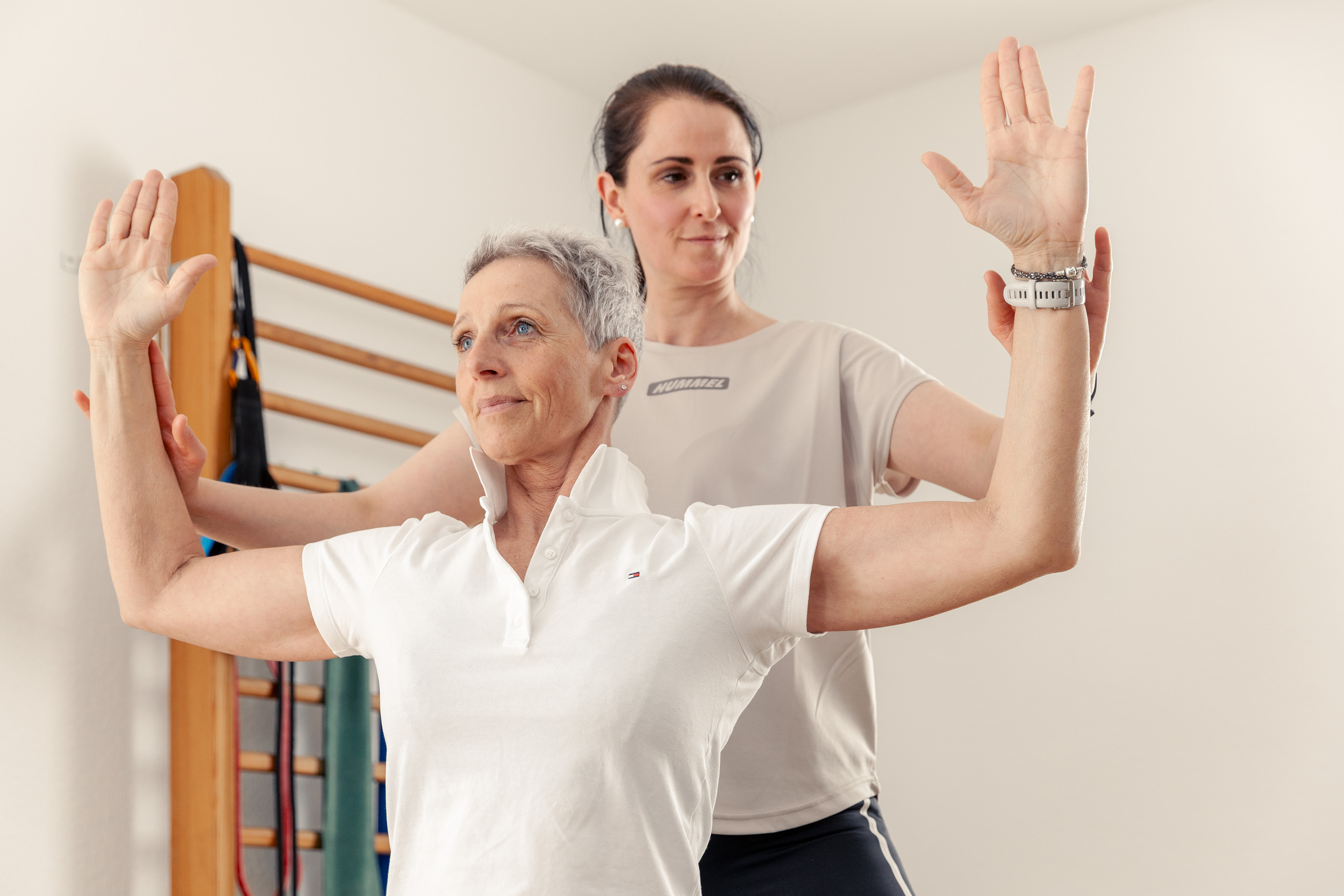 Physiotherapie Hausbesuche | eine Patientin bekommt von einer Physiotherapeutin eine Übung gezeigt