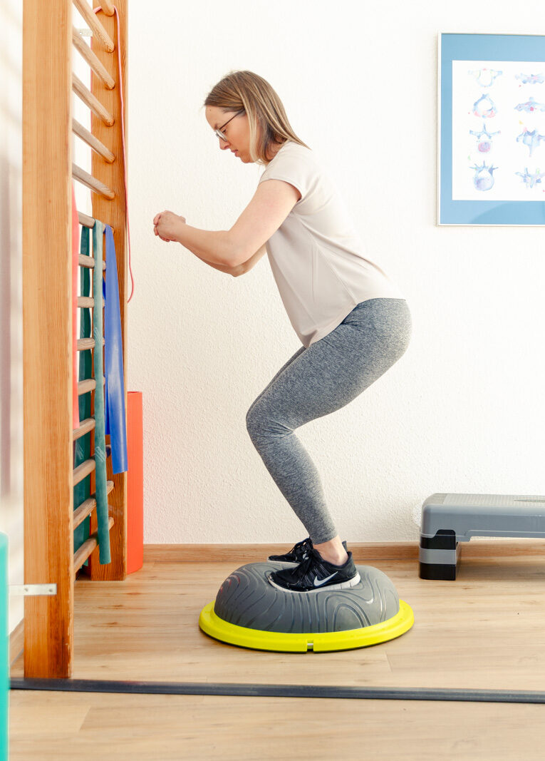 Eine Dame macht Krankengymnastik am Gerät auf einem Balanceball | Physiotherapie Schmeddes