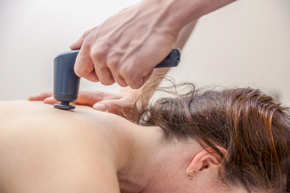 Eine Frau erhält mit einer Massagepistole eine manuelle lymphdrainage in der Nähe bei Physiotherapie Schmeddes